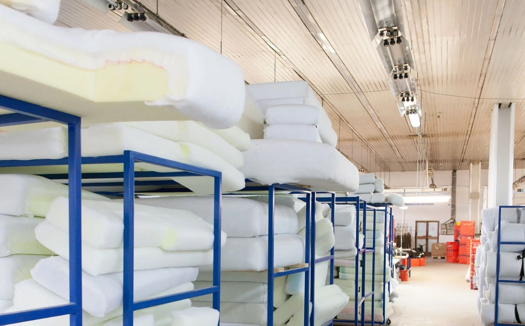 Foam cushions stacked on metal racks in warehouse